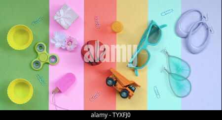 Composition pastel à la mode avec des boucles d'oreilles, lunettes de soleil, des boissons peuvent, le basket-ball ball, camion jouet, boîte-cadeau, glaces, fleurs et spinner Banque D'Images