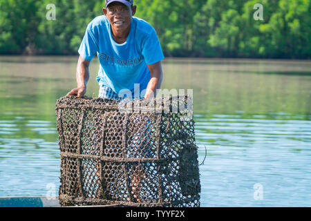 LAHAD DATU Malaisie - 17 mai 2019 ; pêcheur en petit bateau et chemise bleue chèques et déverse le contenu de ses pièges à poissons Banque D'Images