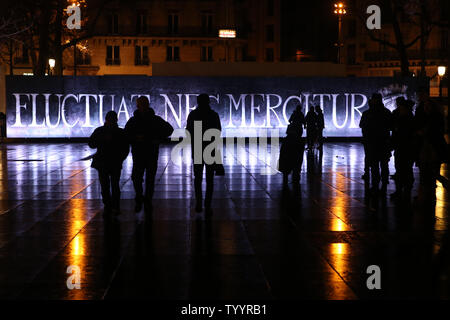 Les gens passent devant un panneau éclairé portant la devise latine de la ville de Paris : "Fluctuat Nec Mergitur" (jeté mais pas Irrécupérable) que les gens se rassemblent pour rendre hommage aux victimes des attaques du mois de janvier dernier à la place de la République à Paris, France, le 10 janvier 2016, marquant le premier anniversaire de la série de tir contre Charlie Hebdo journal hebdomadaire et la technologie d'épicerie Casher qui a coûté 17 vit. . Photo Maya UPI/Vidon-White Banque D'Images