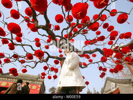 Une jeune chinoise attend que ses parents sous un arbre décoré de lanternes de papier chinois rouge lors d'une foire du temple à Pékin, Chine, le 4 février 2006. Dans le pays chinois a célébré l'année du Chien de différentes façons - de partir des pétards, les quenelles, encens, visiter les foires et les bénédictions du temple s'étendant à des amis et la famille.ÊThe 1,3 milliard de Chinois ont toutes les raisons de revel au début d'une année prometteuse à venir. 2005 ÊIn, le PIB a augmenté de 9,9 pour cent, le maintien d'un taux de croissance rapide qui a duré plus de 20 ans. (UPI Photo/Stephen S Banque D'Images