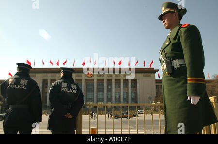 Un soldat de l'Armée de libération du peuple (PLA) (R) et de la police montent la garde en place Tiananmen à côté de la Grande Salle du Peuple (contexte) comme drapeau national rouge géant le signal de début de Congrès National du Peuple à Beijing, Chine, le Jeudi, Mars 02, 2006. Plus de 12 000 soldats armés et la police de Pékin va patrouiller dans les rues et la place d'assurer la sécurité de la capitale chinoise au cours de la séance plénière annuelle de l'Assemblée populaire nationale et de la Conférence consultative politique du peuple chinois. La police de Pékin a lancé un contrôle de sécurité dans toute la ville. (UPI Photo/Stephen Shaver) Banque D'Images