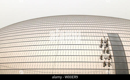 Les travailleurs de la construction accrocher sur le côté de l'oeuf-comme la Dome du Grand Théâtre national chinois au centre-ville de Beijing, le 12 juin 2006. La construction controversée est presque terminé, et l'intérieur sera terminé à la fin de cette année. Conçu par l'architecte français Paul Andreu, les travaux ont commencé en décembre 2001 après quatre années de délibérations entre les décideurs. (UPI Photo/Stephen Shaver) Banque D'Images