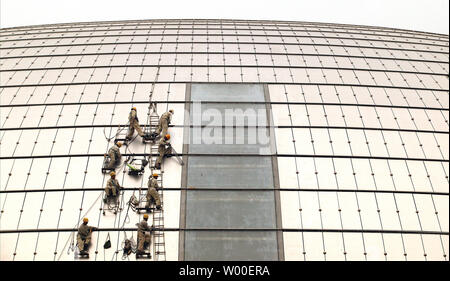 Les travailleurs de la construction accrocher sur le côté de l'oeuf-comme la Dome du Grand Théâtre national chinois au centre-ville de Beijing, le 12 juin 2006. La construction controversée est presque terminé, et l'intérieur sera terminé à la fin de cette année. Conçu par l'architecte français Paul Andreu, les travaux ont commencé en décembre 2001 après quatre années de délibérations entre les décideurs. (UPI Photo/Stephen Shaver) Banque D'Images