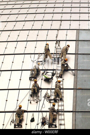 Les travailleurs de la construction accrocher sur le côté de l'oeuf-comme la Dome du Grand Théâtre national chinois au centre-ville de Beijing, le 12 juin 2006. La construction controversée est presque terminé, et l'intérieur sera terminé à la fin de cette année. Conçu par l'architecte français Paul Andreu, les travaux ont commencé en décembre 2001 après quatre années de délibérations entre les décideurs. (UPI Photo/Stephen Shaver) Banque D'Images