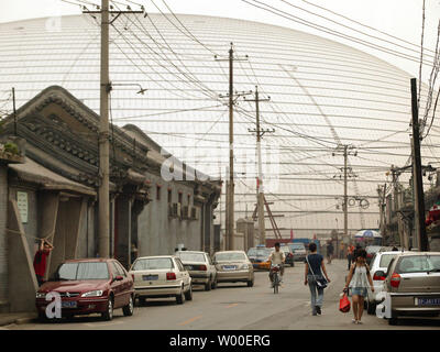 L'oeuf-comme la Dome du Grand Théâtre national chinois se lève au-dessus des maisons voisines au centre-ville de Beijing, le 12 juin 2006. La construction controversée est presque terminé, et l'intérieur sera terminé à la fin de cette année. Conçu par l'architecte français Paul Andreu, les travaux ont commencé en décembre 2001 après quatre années de délibérations entre les décideurs. (UPI Photo/Stephen Shaver) Banque D'Images