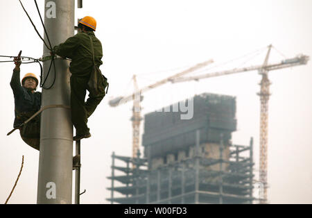 Deux employés de la ville chinois travaillent sur les lignes téléphoniques au centre-ville de Beijing, Chine le 8 décembre 2006. Avec la poussée agressive de modernisation, y compris les gratte-ciel modernes et super-autoroutes, les grandes villes du pays ont connu des changements importants dans les deux horizons et de l'infrastructure. (UPI Photo/Stephen Shaver) Banque D'Images