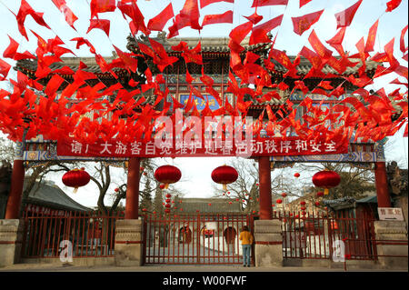 Une femme attend pour un moine pour ouvrir la porte verrouillée du Temple taoïste Baiyunguan, décoré pour le Nouvel An le festival du printemps, dans le centre de Pékin, Chine le 17 février 2007. La nouvelle année lunaire, ou Fête du printemps, le dimanche commence à entrer dans l'année du cochon, mais les Chinois ont été l'embarquement les trains et les avions depuis plusieurs semaines à la maison pour les réunions de famille. (UPI Photo/Stephen Shaver) Banque D'Images