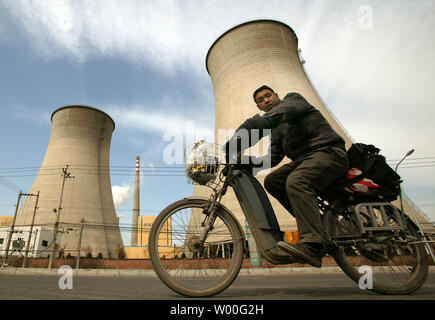 Un homme sur un "boguet rides passé une énorme centrale électrique sur la périphérie de Beijing, Chine Le 27 mars 2007. Le Premier ministre chinois Wen Jiabao s'est engagé ce mois que son gouvernement d'honorer ses responsabilités internationales et de réduire les émissions de gaz à effet de serre. (UPI Photo/Stephen Shaver) Banque D'Images