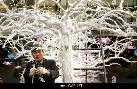 Les travailleurs chinois ont mis en place les décorations de Noël en face d'immeubles de bureaux au centre-ville de Beijing, Chine Le 28 novembre 2007. Capitale de la Chine c'est d'attraper la fièvre de Noël comme la plupart des nouveaux centres commerciaux de Pékin moderne sont ornées d'arbres, le thistle, rubans et de cloches en prévision d'une augmentation de la demande de produits dérivés et de shopping. (UPI Photo/Stephen Shaver) Banque D'Images