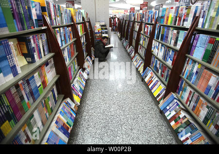 Un Chinois lit un livre tout en restant assis sur le sol entre les rangs des rayons de livres dans l'une des librairies du gouvernement de Beijing le 28 janvier 2010. Le gouvernement de la Chine maintient toujours une prise ferme sur la publication de livres, le contenu des programmes de radio et de télévision, ainsi que le contrôle sur l'accès à des sites internet. UPI/Stephen Shaver Banque D'Images