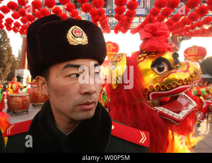 Un policier militaire monte la garde en tant que musiciens et danseurs chinois exécuter une danse du lion sous Red Lantern décorations lors de la cérémonie d'ouverture du Festival de Printemps Foire du Temple au Temple de la Terre à Beijing le 14 février 2010. Le Nouvel An chinois, ou Fête du Printemps, est la plus grande maison de la Chine, les travailleurs migrants donnant leur seule chance de retourner dans leurs provinces d'origine avec des cadeaux et de l'argent pour la famille. Il représente la plus grande migration de masse annuelle de l'homme. UPI/Stephen Shaver Banque D'Images