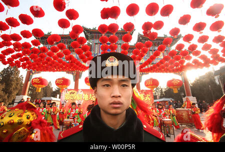 Un policier militaire monte la garde en tant que musiciens et danseurs chinois exécuter une danse du lion sous Red Lantern décorations lors de la cérémonie d'ouverture du Festival de Printemps Foire du Temple au Temple de la Terre à Beijing le 14 février 2010. Le Nouvel An chinois, ou Fête du Printemps, est la plus grande maison de la Chine, les travailleurs migrants donnant leur seule chance de retourner dans leurs provinces d'origine avec des cadeaux et de l'argent pour la famille. Il représente la plus grande migration de masse annuelle de l'homme. UPI/Stephen Shaver Banque D'Images