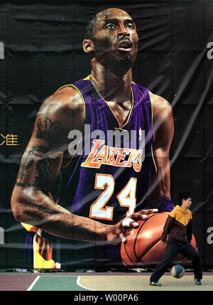 Un étudiant chinois dribble un ballon de basket en face d'une gigantesque affiche de la superstar de la NBA Kobe Bryant à Beijing le 23 février 2010. UPI/Stephen Shaver Banque D'Images