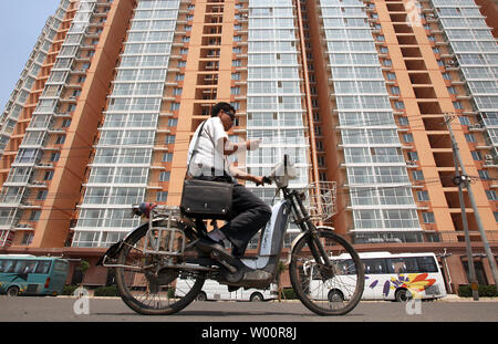 Un Chinois chevauche son cyclomoteur passé un nouveau, encore vide, propriété résidentielle dans le centre de Pékin, le 5 juillet 2010. La Chine, avec déjà plus de 160 villes de plus de 1 millions de dollars, est sur le point de devenir un pays urbain. La population du pays, la plus grande du monde à venir de l'Inde, devrait augmenter d'environ 1,4 milliards de dollars en 2015 de 1,32 milliards de dollars en 2008. Plus de la moitié de sa population vivra dans des villes d'ici là, la population nationale et de la Commission de planification familiale a dit. UPI/Stephen Shaver Banque D'Images