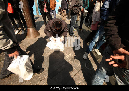 Des groupes de Chinois s'attarder à l'extérieur du magasin phare d'Apple dans l'espoir de la corruption pour les acheteurs leur carte d'identité afin d'acheter des iPhones à Beijing le 3 avril 2011. Les hommes, qui paient en espèces et utiliser 'mules' d'acheter jusqu'à 60 iPhones par jour, alors à la vente des téléphones portables à des prix plus élevés en dehors de Beijing. Limites Apple achète à deux iphone par personne, et pour décourager les visites répétées il tient un registre des cartes de crédit utilisées, mais les achats en espèces ne sont pas suivis. Apple dit la limite 'aide à s'assurer qu'il y a suffisamment d'iphone pour les personnes qui font des achats pour eux-mêmes ou d'acheter un cadeau." Banque D'Images