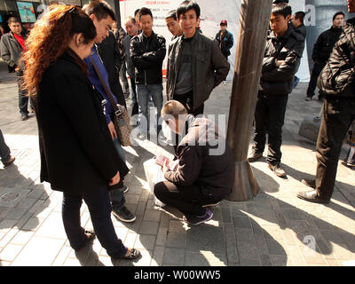 Des groupes de Chinois s'attarder à l'extérieur du magasin phare d'Apple dans l'espoir de la corruption pour les acheteurs leur carte d'identité afin d'acheter des iPhones à Beijing le 3 avril 2011. Les hommes, qui paient en espèces et utiliser 'mules' d'acheter jusqu'à 60 iPhones par jour, alors à la vente des téléphones portables à des prix plus élevés en dehors de Beijing. Limites Apple achète à deux iphone par personne, et pour décourager les visites répétées il tient un registre des cartes de crédit utilisées, mais les achats en espèces ne sont pas suivis. Apple dit la limite 'aide à s'assurer qu'il y a suffisamment d'iphone pour les personnes qui font des achats pour eux-mêmes ou d'acheter un cadeau." Banque D'Images