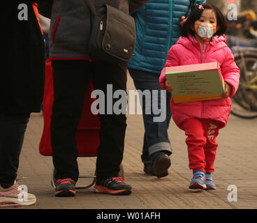 Une jeune fille chinoise porte un masque de filtre à air en marchant avec ses parents à Pékin le 10 mars 2016. La Chine va intensifier ses efforts pour réduire la pollution atmosphérique, en citant un exemple des objectifs ambitieux dans la lutte contre le smog qui permettra d'accroître le nombre de jours avec une bonne qualité de l'air. Photo par Stephen Shaver/UPI Banque D'Images