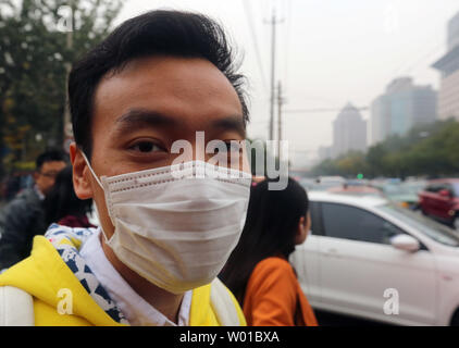 Un Chinois porte un masque de visage pour protéger contre le lourd brouillard qui plane au-dessus de Beijing le 17 novembre 2016. Capitale de la Chine a mis en garde ses 20 millions d'habitants pour limiter les activités de plein air pour éviter les effets néfastes d'une forte pollution couvrant la ville. Photo par Stephen Shaver/UPI Banque D'Images