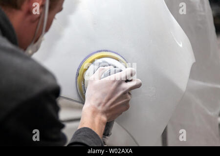 Préparation pour la peinture d'une voiture à l'aide de l'élément sander et putty par un technicien de nivellement avant l'application d'un primaire après l'endommagement d'une partie de Banque D'Images