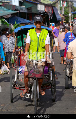 Un chauffeur avec un des quelques samlor ou trois roues vélos-pousse en Thaïlande, dans un marché à Nonthaburi près de Bangkok Banque D'Images