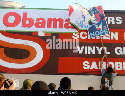 Un manifestant utilise un signe de piquetage à rip vers le bas une bannière qu'une entreprise avait accroché d'accueillir le président américain Barack Obama à Oakland à Oakland, Californie le 23 juillet 2012. Obama était en ville pour assister une collecte du Fox Theatre. Plusieurs centaines de manifestants ont protesté de sa visite. UPI/David Yee Banque D'Images