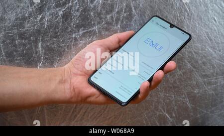 Man holding smartphone Huawei Mate 20 X dans une main sur fond gris brillant. L'affichage est allumé et les paramètres de menu avec téléphones général configurato Banque D'Images