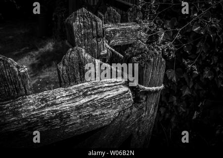 Une image en noir et blanc d'une vieille porte en bois fermée avec une corde. Banque D'Images