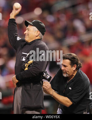 Accueil arbitre John Hirschbeck lance une balle de baseball à la cruche comme un spécialiste de l'audio de la télévision ESPN vérifie son microphone sans fil pendant un match entre les Reds de Cincinnati et les Cardinals de Saint-Louis au Busch Stadium de Saint-Louis le 24 avril 2011. UPI/Bill Greenblatt Banque D'Images