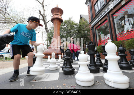 Les enfants jouent sur un grand jeu d'échecs à côté de la plus grande pièce d'échecs à l'extérieur du monde d'Échecs Hall of Fame and Museum à St Louis le 13 avril 2018. Le king chess piece certifié par Guinness World Records, les peuplements de 20 pieds de haut avec une base de 9 pieds, 2 pouces, et est une échelle exacte réplique de la pièce King Staunton noir utilisé dans la première tasse Sinquefield tenue au Club d'échecs de Saint Louis par an depuis 2013. Photo de Bill Greenblatt/UPI Banque D'Images