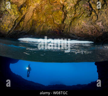 La moitié au-dessus, la moitié inférieure de la diver (MR) à l'entrée d'une caverne qui brise la surface de l'île de Gato, la mer de Bohol, Philippines, Southea Banque D'Images