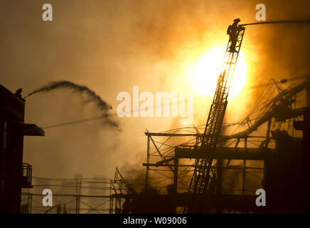 Le soleil qui brûle à travers la fumée que les pompiers, verser de l'eau sur un plan d'alarme de feu dans des appartements en construction dans le quartier du bassin de la Chine de San Francisco le 11 mars 2014. UPI/Terry Schmitt Banque D'Images