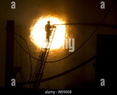 Le soleil qui brûle à travers la fumée que les pompiers, verser de l'eau sur un plan d'alarme de feu dans des appartements en construction dans le quartier du bassin de la Chine de San Francisco le 11 mars 2014. UPI/Terry Schmitt Banque D'Images