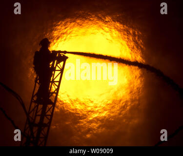 Le soleil qui brûle à travers la fumée que les pompiers, verser de l'eau sur un plan d'alarme de feu dans des appartements en construction dans le quartier du bassin de la Chine de San Francisco le 11 mars 2014. UPI/Terry Schmitt Banque D'Images