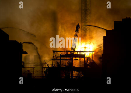 Le soleil qui brûle à travers la fumée que les pompiers, verser de l'eau sur un plan d'alarme de feu dans des appartements en construction dans le quartier du bassin de la Chine de San Francisco le 11 mars 2014. UPI/Terry Schmitt Banque D'Images