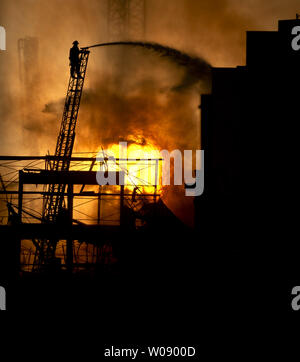 Le soleil qui brûle à travers la fumée que les pompiers, verser de l'eau sur un plan d'alarme de feu dans des appartements en construction dans le quartier du bassin de la Chine de San Francisco le 11 mars 2014. UPI/Terry Schmitt Banque D'Images