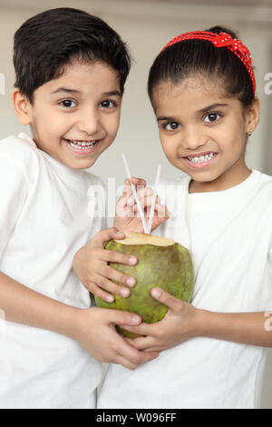 Portrait of two children smiling and drinking coconut water Stock Photo