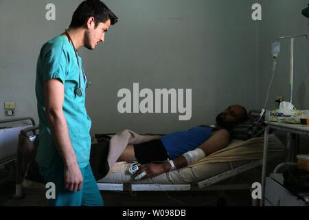 Un médecin syrien aide un homme blessé à l'hôpital. Après les frappes aériennes russes a frappé à Alep, province de Syrie le 21 mai 2016. La reprise des combats au cours des derniers jours, en particulier dans et autour d'Alep, a menacé l'effondrement d'un accord de cessez-le-feu, un point de repère dans les tentatives pour enfin régler un conflit qui a fait plus de 270 000 morts. Photo par Ameer Alhalbi/ UPI Banque D'Images