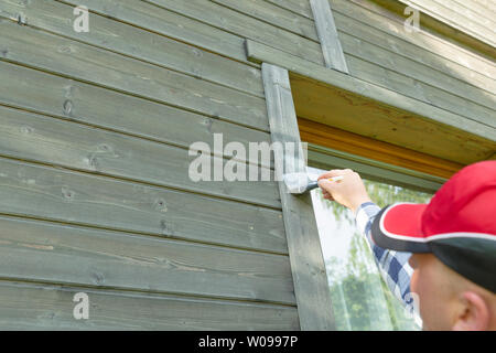 Maison en bois peinture travailleur homme mur extérieur avec pinceau et couleur de protection du bois Banque D'Images