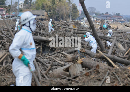 La police japonaise portant des tenues de protection contre les agents chimiques recherche de victimes à l'intérieur du rayon de 20 kilomètres autour de la centrale nucléaire de Fukushima Dai-ichi power plant à Minamisoma, préfecture de Fukushima, au Japon, le 15 avril 2011. Un tremblement de terre et le tsunami qui a suivi le 11 mars détruit les maisons, tué des milliers de personnes et causé une catastrophe nucléaire. UPI/Keizo Mori Banque D'Images