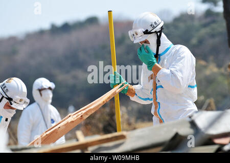 La police japonaise portant des tenues de protection contre les agents chimiques recherche de victimes à l'intérieur du rayon de 20 kilomètres autour de la centrale nucléaire de Fukushima Dai-ichi power plant à Minamisoma, préfecture de Fukushima, au Japon, le 15 avril 2011. Un tremblement de terre et le tsunami qui a suivi le 11 mars détruit les maisons, tué des milliers de personnes et causé une catastrophe nucléaire. UPI/Keizo Mori Banque D'Images