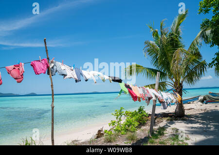 Vêtements lavés et suspendu dans le vent et soleil tropical à sécher entre les palmiers sur la plage. Banque D'Images