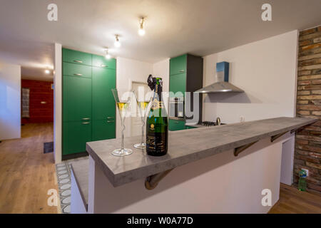 De nouveaux meubles de cuisine vert avec bouteille de champagne et deux verres au bar Banque D'Images