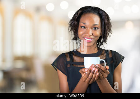 Jeune femme africaine de boire du café tout en travaillant au bureau Banque D'Images