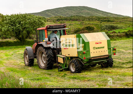 Ballydehob, West Cork, Irlande. 27 juin 2019. Michael Pat Ward, un agriculteur basé à Durrus, navigue de l'herbe pour l'ensilage sous le regard du mont Corrin. Les balles seront utilisées comme alimentation d'hiver pour le bétail. Crédit : AG News/Alay Live News. Banque D'Images