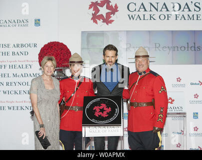 Joine par sa mère Tammy (L) et encadré par des agents de la GRC l'acteur Ryan Reynolds dévoile son étoile sur le tapis jaune où il sera intronisé dans le 2014 l'Allée des célébrités canadiennes lors de cérémonies au Sony Centre for the Performing Arts à Toronto (Ontario) le 18 octobre 2014. UPI/Heinz Ruckemann Banque D'Images