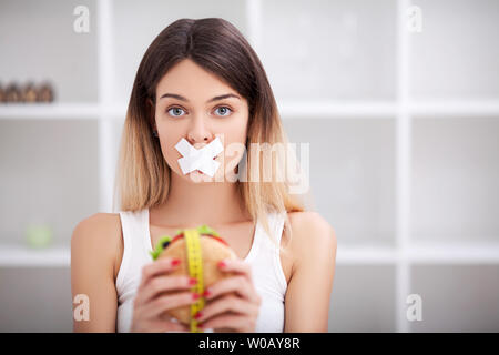 Régime alimentaire. Close up visage de jeune belle femme latine triste avec la bouche scellée sur stick tape Banque D'Images