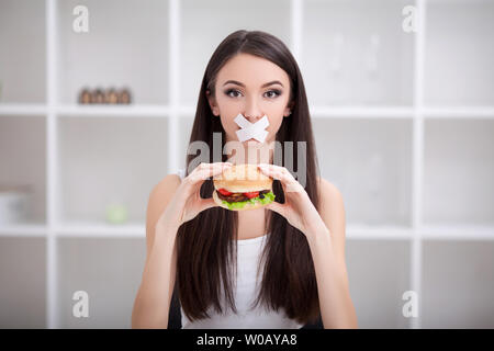 Régime alimentaire. Close up visage de jeune belle femme latine triste avec la bouche scellée sur stick tape Banque D'Images