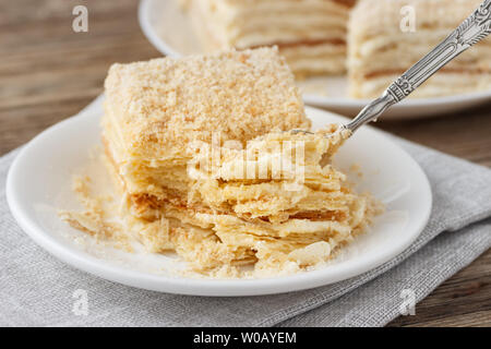 Gâteau de couches avec crème vanille millefeuille Napoléon tranche sur une assiette blanche. Banque D'Images