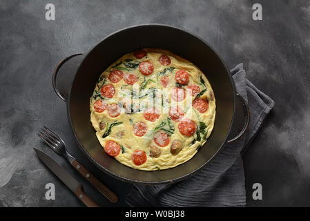 La frittata en oeufs, champignons, tomates cerises et les épinards dans une casserole. La cuisine Italienne Banque D'Images