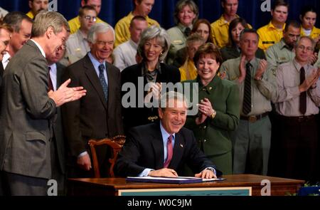 Le Président George Bush signe la Loi sur la restauration des forêts en bonne santé le 3 décembre 2003 à Washington, en tant que secrétaire de l'Agriculture, Ann M. Veneman, droite, Secrétaire à l'intérieur Gale Norton, A.gauche, membres du Congrès et des travailleurs de l'oeil. Le projet de loi est censé renforcer la participation du public à l'entretien des forêts des nations unies et de limiter les incendies de forêt qui ravagent chaque année la partie ouest du pays. (Photo d'UPI/Michael Kleinfeld) Banque D'Images